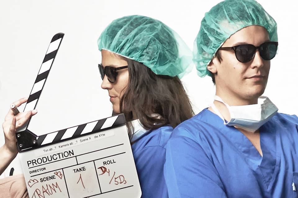 Zwei Ärzte mit Sonnenbrille und eine Filmklappe